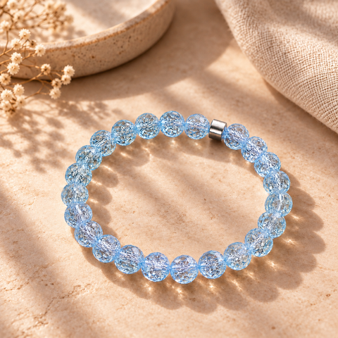 Ipanema Bergkristall-Armband mit facettierten aquamarinblauen Perlen auf warmem beigefarbenem Hintergrund.