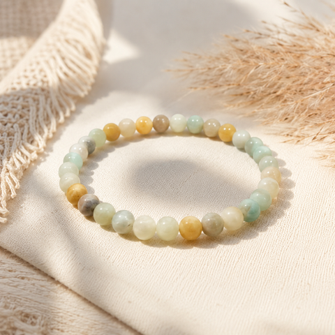 Frau trägt das filigrane Avena Natursteinarmband mit 6 mm großen Perlen in Mintgrün, Creme, Beige und warmen Gelbtönen in einer natürlichen, sonnigen Umgebung.