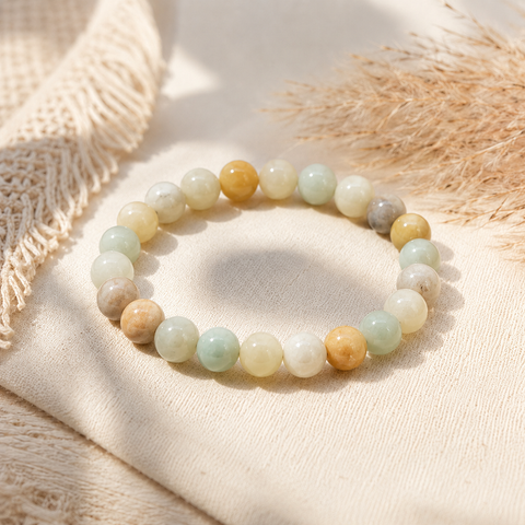 Avena Natursteinarmband mit 8 mm großen, polierten Perlen in Mintgrün, Cremeweiß, Beige, Grau und Honiggelb auf hellem Leinen mit natürlichen Gräsern präsentiert.