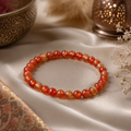 Helles Karneol-Natursteinarmband mit 6 mm großen, transparenten Perlen in Orange, Rot und Honiggelb auf einem dezenten orientalischen Stoff mit warmen Dekoelementen.