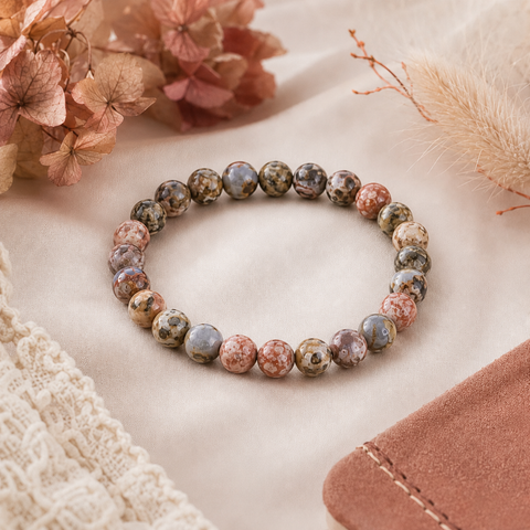 Leopard Skin Jasper Natursteinarmband mit 8 mm großen Perlen und abwechslungsreicher Maserung in Rot-, Creme-, Grau- und Brauntönen auf einem hellen, weich inszenierten Untergrund.