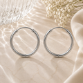 Luna Creolen in Silber mit 20 mm Durchmesser aus hochwertigem Edelstahl. Klassische große Creolen mit glänzender Oberfläche, stilvoll inszeniert auf heller Natursteinoptik mit sanften Lichtreflexionen, Glasstruktur, weißen Blüten und elegantem Stoff im Hintergrund. Zeitloser Ohrschmuck für Alltag und besondere Anlässe.
