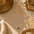 Filigrane Nazar Fußkette in Gold mit blauem Schutzauge als orientalischem Glücksbringer. Stilvoll präsentiert in einer warmen mediterranen Umgebung mit feinen Ornamenten, goldenem Licht und sommerlicher Eleganz. Ein ausdrucksstarkes Schmuckstück für Urlaub, Alltag und besondere Anlässe.