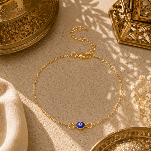 Filigrane Nazar Fußkette in Gold mit blauem Schutzauge als orientalischem Glücksbringer. Stilvoll präsentiert in einer warmen mediterranen Umgebung mit feinen Ornamenten, goldenem Licht und sommerlicher Eleganz. Ein ausdrucksstarkes Schmuckstück für Urlaub, Alltag und besondere Anlässe.