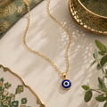 Goldene Nazar Halskette mit klassischem dunkelblauem Nazar Auge Anhänger auf luxuriösem beige-grünem Hintergrund mit orientalischen Details und warmen Lichtreflexen.