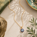 Nazar Halskette mit hellblauem Nazar Auge Anhänger auf hochwertigem beigefarbenem Hintergrund mit orientalischen Grün- und Goldakzenten im warmen mediterranen Stil.