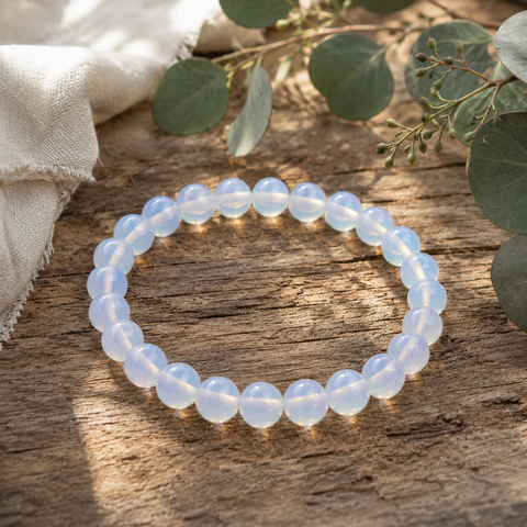 Opalite-Armband mit 8 mm großen, leicht transparenten Perlen in milchigem Weiß und zartem Blau auf verwittertem Holz mit Eukalyptus und hellem Naturstoff präsentiert.