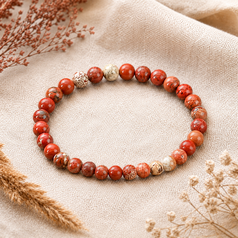 Red Jasper Natursteinarmband mit 6 mm großen, individuell gemusterten Perlen in Rot-, Terrakotta-, Braun- und Cremetönen auf hellem Naturstoff mit farblich passenden Trockenblumen.