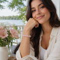 Rosenquarz-Natursteinarmband mit 8 mm großen, polierten Perlen in sanftem Rosa auf einer natürlich strukturierten Steinfläche mit rosa Blüten und weißen Trockenblumen.