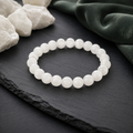 São Paulo Weiß-Jade-Armband mit 8 mm großen, milchig weißen und sanft gemaserten Perlen auf schwarzem Schiefer mit weißen Steinen und dunkelgrünem Stoff.