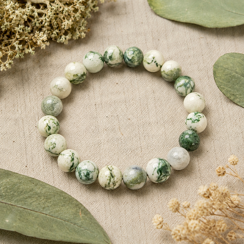 Tree Agate Natursteinarmband mit 8 mm großen, grün-weiß marmorierten Perlen auf beigefarbenem Naturstoff, umgeben von Eukalyptusblättern und feinen Trockenblüten.