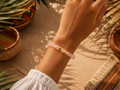Aprikotfarbenes Bergkristall-Armband mit 8 mm großen Perlen im Diamantschliff an gebräuntem Handgelenk getragen, inszeniert in warmer südamerikanischer Atmosphäre.