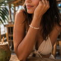 Aprikotfarbenes Bergkristall-Armband mit 8 mm großen Perlen im Diamantschliff am gebräunten Handgelenk getragen, natürlich inszeniert in warmer Strandbar-Atmosphäre.