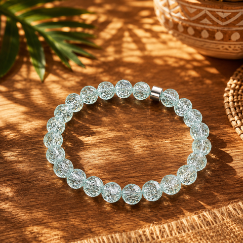 Aquamarinfarbenes Bergkristall-Armband mit 8 mm großen Perlen im Diamantschliff auf warmem Holzuntergrund mit Palmenschatten und südamerikanisch inspirierten Naturdetails.