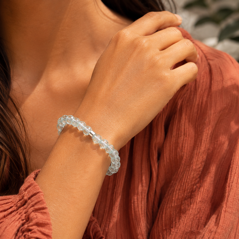Aquamarinfarbenes Bergkristall-Armband mit 8 mm großen Perlen im Diamantschliff am gebräunten Handgelenk getragen, kombiniert mit rostfarbenem Oberteil und warmer südamerikanischer Atmosphäre.