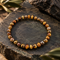 Atacama Tigerauge Armband mit 6-mm-Perlen in Gold-, Honig- und Brauntönen auf dunklem Naturstein.