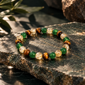 Elarûn Mixed Naturstein Armband mit grünen, goldbraunen und transparenten Perlen auf dunklem Naturstein.