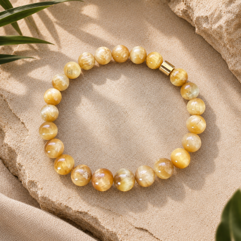 Gelbes Natursteinarmband mit 8-mm-Perlen in Creme-, Honig- und Goldtönen mit goldfarbenem Akzent auf hellem Naturstein.