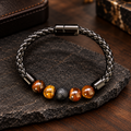 KAIO Armband mit warmen Tigerauge-Perlen, dunklem Lavastein und schwarzem geflochtenem Band.