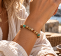 Frau trägt das KUNENE Aventurin & Landschaftsjaspis Armband mit grünen Aventurin- und braunen Natursteinperlen am Handgelenk.