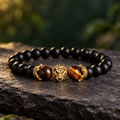 LEONIS Gold Löwenkopf Armband mit mattschwarzen 8-mm-Perlen, braun-goldenem Tigerauge und goldfarbenen Details.