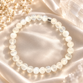 Naxos Selenit Armband mit weißen 6-mm-Natursteinperlen und silberfarbenem Akzent auf hellem Satin.