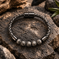 NOX Armband mit strukturierten grauen Lavastein-Perlen und schwarzem geflochtenem Band.