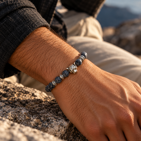 Mann trägt das ONYRÂME Silver Armband mit schwarzen Achat-Perlen und silbernem Leopardenkopf in natürlicher Outdoor-Umgebung.