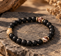 SAVANNA Classic Naturstein Armband mit mattschwarzen 8-mm-Perlen, drei creme-braun marmorierten Akzentsteinen und goldfarbenen Details.