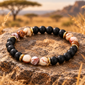 SAVANNA Mosaic Naturstein Armband mit mattschwarzen 8-mm-Perlen, neun creme-braun marmorierten Akzentsteinen und goldfarbenen Details.