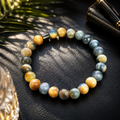 Tigerauge-Armband mit 8-mm-Perlen in Blau-, Grau-, Gold- und Brauntönen auf dunklem, eleganten Hintergrund mit warmem Licht und stilvollen Accessoires.