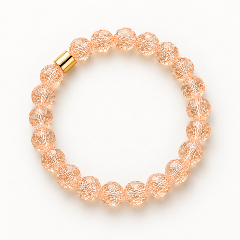 Facettiertes Bergkristall-Armband in Pfirsich mit Goldakzent auf weißem Hintergrund.
