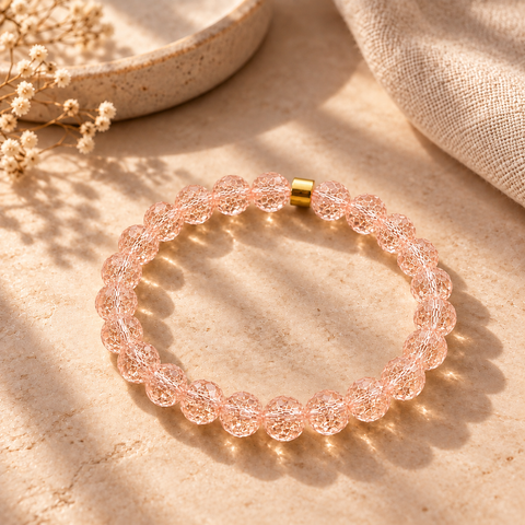 Cartagena Bergkristall-Armband mit facettierten roséfarbenen Perlen auf warmem beigefarbenem Hintergrund.