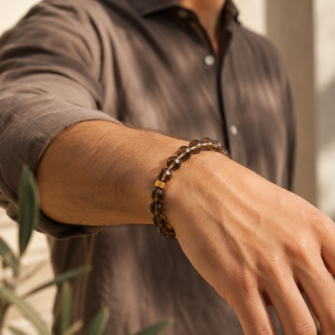 Person trägt ein facettiertes Rauchquarz-Armband mit 8 mm großen braunen Perlen und goldfarbener Akzentperle frontal am Handgelenk.