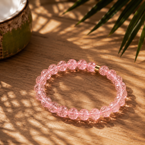Roséfarbenes Bergkristall-Armband mit 8 mm großen Perlen im Diamantschliff auf warmem Holzuntergrund mit Palmenschatten und südamerikanisch inspirierten Naturdetails.