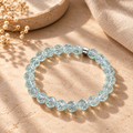 Selva Bergkristall-Armband mit facettierten mintfarbenen Perlen auf warmem beigefarbenem Hintergrund.
